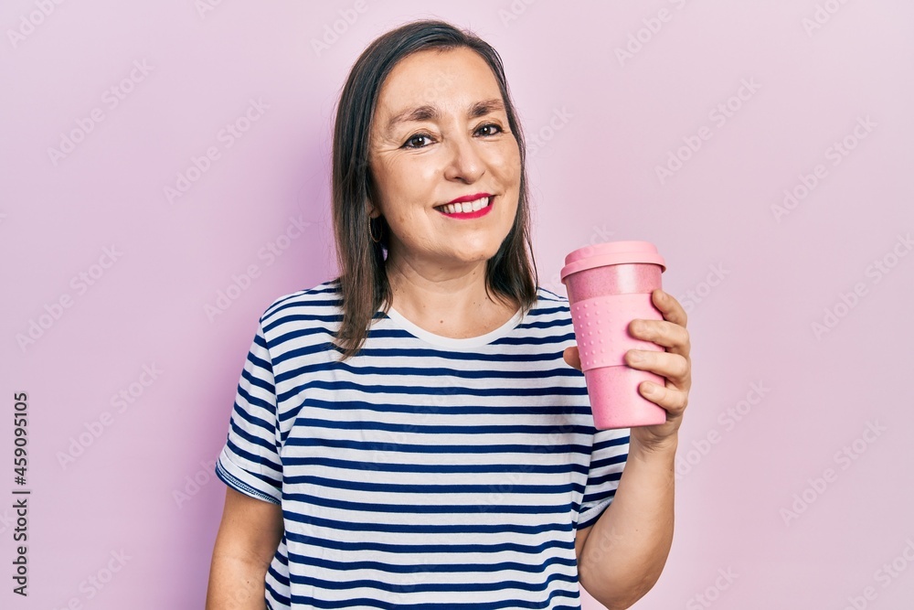 Middle age hispanic woman holding coffee looking positive and happy standing and smiling with a confident smile showing teeth Middle age hispanic woman holding coffee looking positive and happy standing and smiling with a confident smile showing teeth
