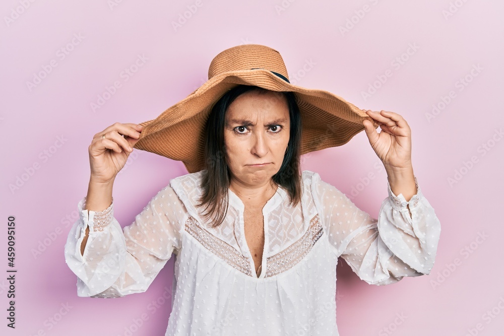 Middle age hispanic woman wearing summer hat skeptic and nervous, frowning upset because of problem. negative person. Middle age hispanic woman wearing summer hat skeptic and nervous, frowning upset because of problem. negative person.