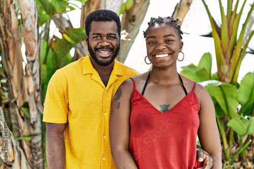 Young african american couple wearing casual clothes standing at the city looking positive and happy standing and smiling with a confident smile showing teeth © Krakenimages.com