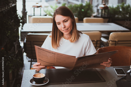 Stylish young woman in street cafe reading menu photo