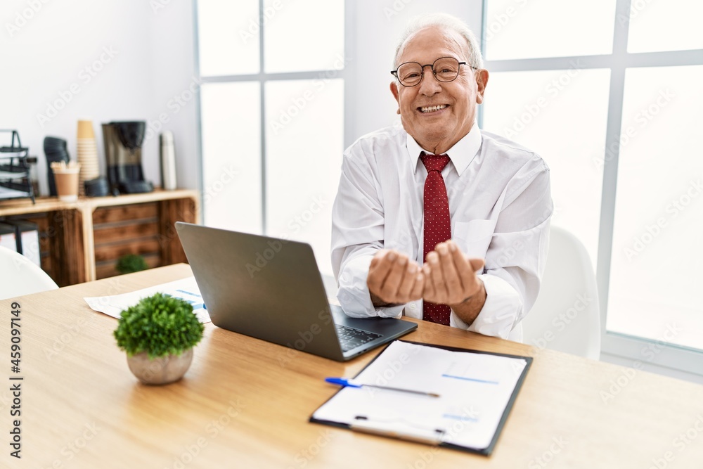 Senior man working at the office using computer laptop smiling with hands palms together receiving or giving gesture. hold and protection Senior man working at the office using computer laptop smiling with hands palms together receiving or giving gesture. hold and protection