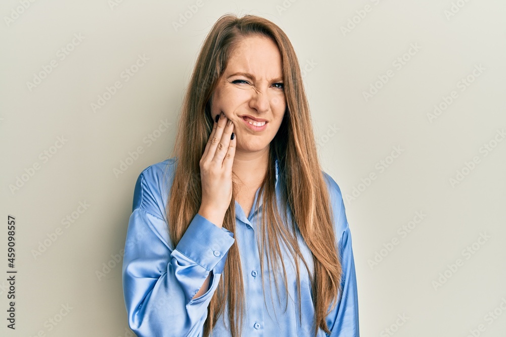 Young blonde woman wearing casual blue shirt touching mouth with hand with painful expression because of toothache or dental illness on teeth. dentist Young blonde woman wearing casual blue shirt touching mouth with hand with painful expression because of toothache or dental illness on teeth. dentist