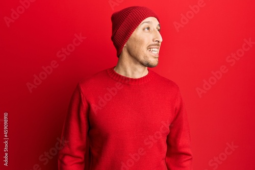 Bald man with beard wearing wool sweater and winter hat looking to side, relax profile pose with natural face and confident smile.