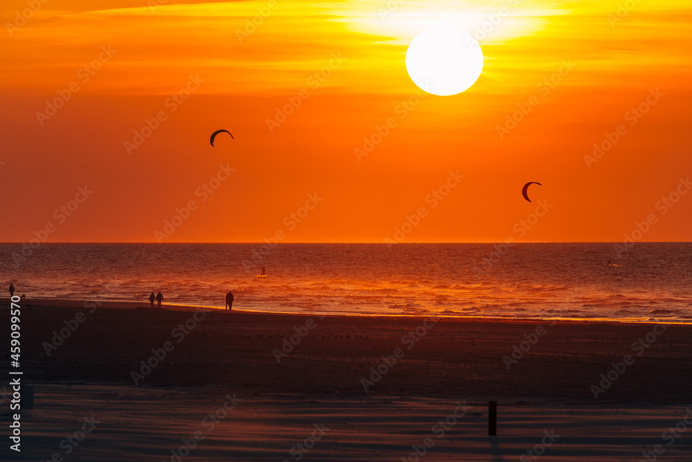 setting sun in the sea, on the beach of Ameland, north sea, wadden sea, beautiful warm golden and yellow colors 