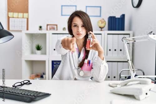 Young doctor woman holding electronic cigarette at medical clinic pointing with finger to the camera and to you  confident gesture looking serious