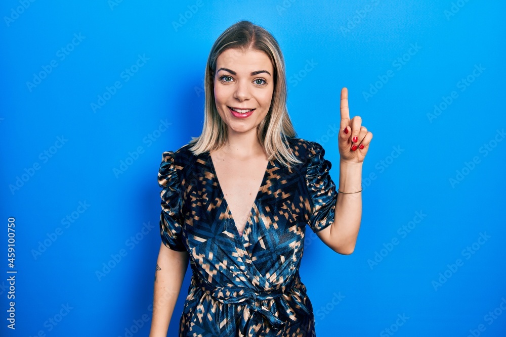 Fototapeta premium Beautiful caucasian woman wearing elegant party dress pointing finger up with successful idea. exited and happy. number one.