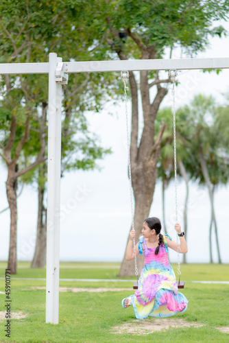 A young girl, wearing a colorful dress, sits on a swing at the playground. of the hotel where she stayed