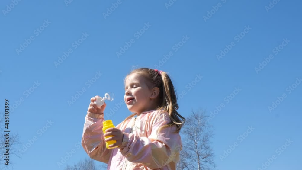 Happy child girl blowing soap bubbles . Active child walking in the park. Family lifestyle, outdoors activities, summer holidays with kids. Slow motion Happy child girl blowing soap bubbles . Active child walking in the park. Family lifestyle, outdoors activities, summer holidays with kids. Slow motion