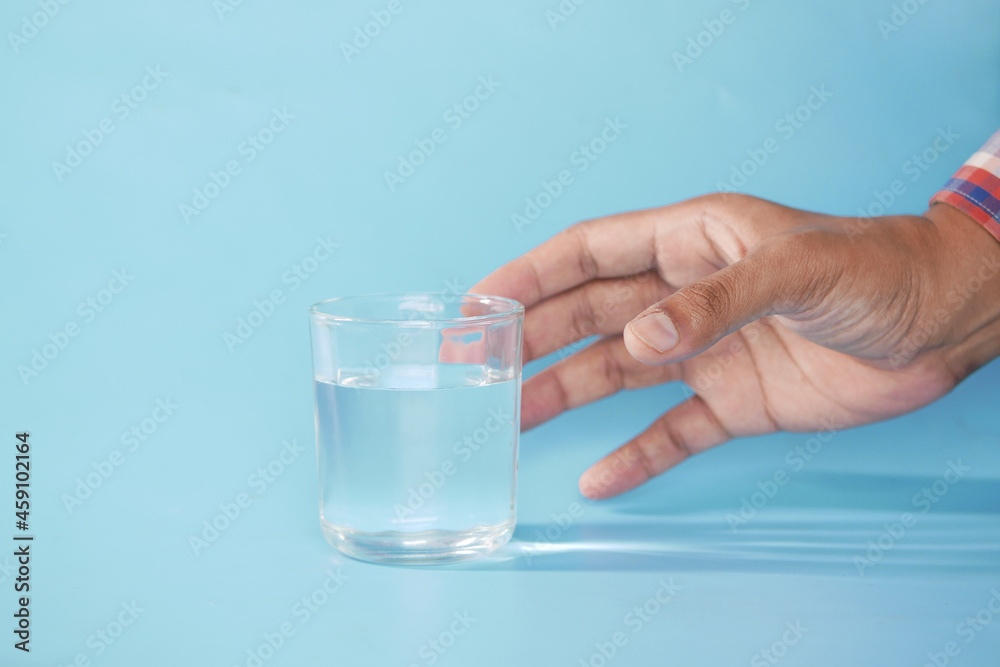 hand holding a glass of water against blue background hand holding a glass of water against blue background