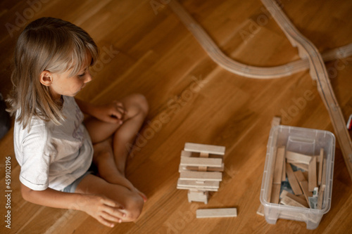 girl 7 years old plays at home with toys. Girl builds a tower from wooden sticks