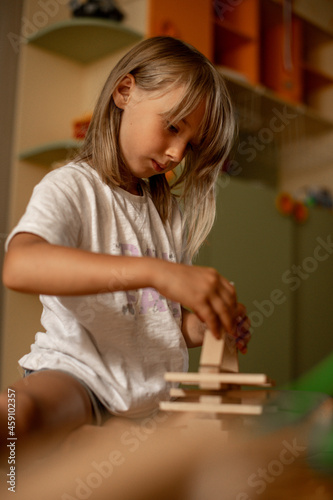girl 7 years old plays at home with toys. Girl builds a tower from wooden sticks