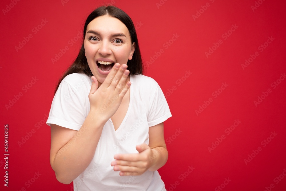 Photo of positive young beautiful brunette woman with sincere emotions wearing white t-shirt for mockup isolated over red background with empty space and laughing Photo of positive young beautiful brunette woman with sincere emotions wearing white t-shirt for mockup isolated over red background with empty space and laughing