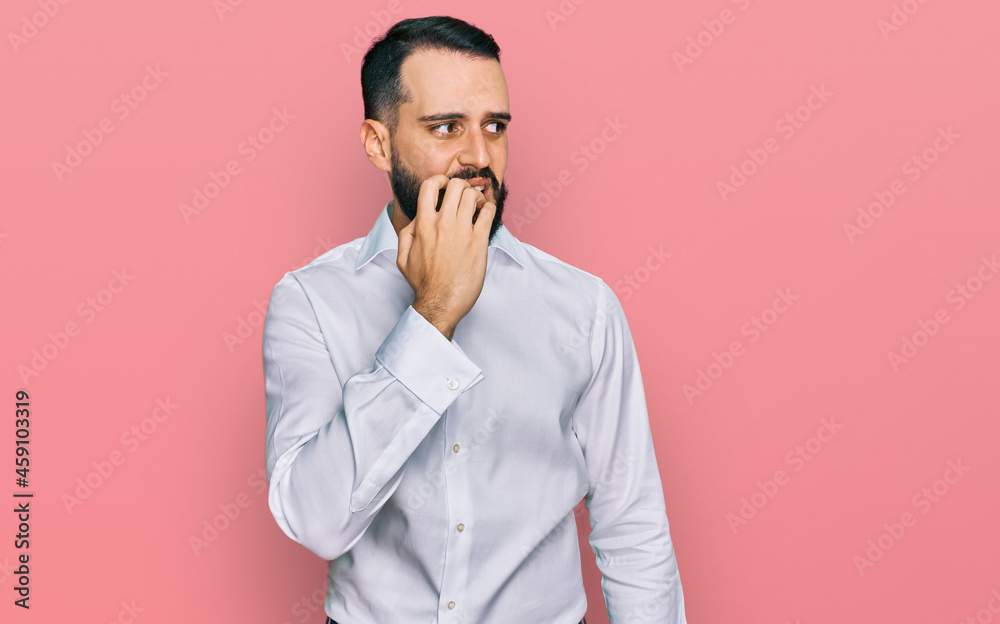 Young man with beard wearing business shirt looking stressed and nervous with hands on mouth biting nails. anxiety problem. Young man with beard wearing business shirt looking stressed and nervous with hands on mouth biting nails. anxiety problem.