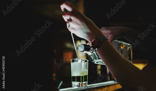 bartender hand making collection of colorful shots. two cocktails at the bar counter