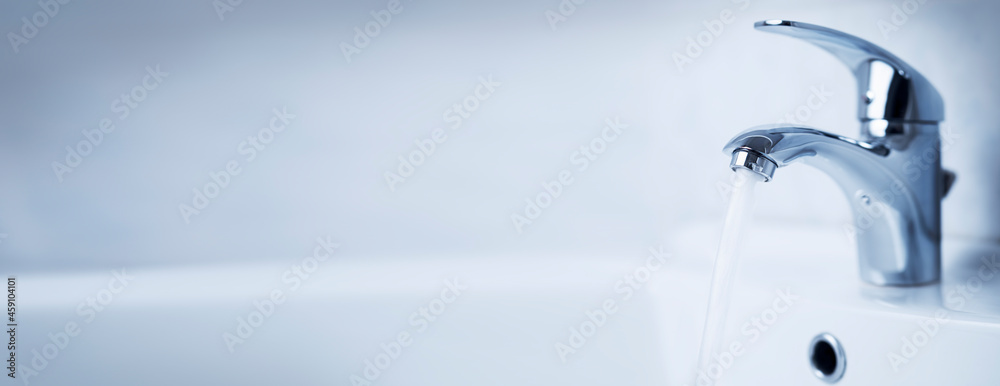 Water tap, stainless steel faucet. Water flow in bathroom with sink. Modern clean house interior. Hygiene concept. Panorama. Water tap, stainless steel faucet. Water flow in bathroom with sink. Modern clean house interior. Hygiene concept. Panorama.