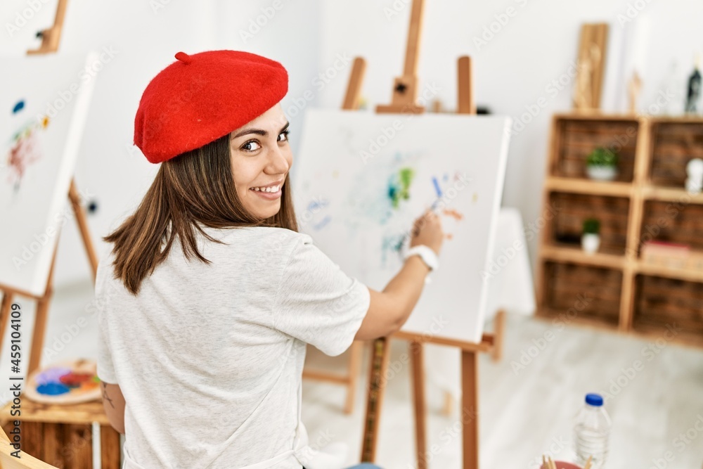 Young hispanic artist woman wearing french beret drawing at art studio.