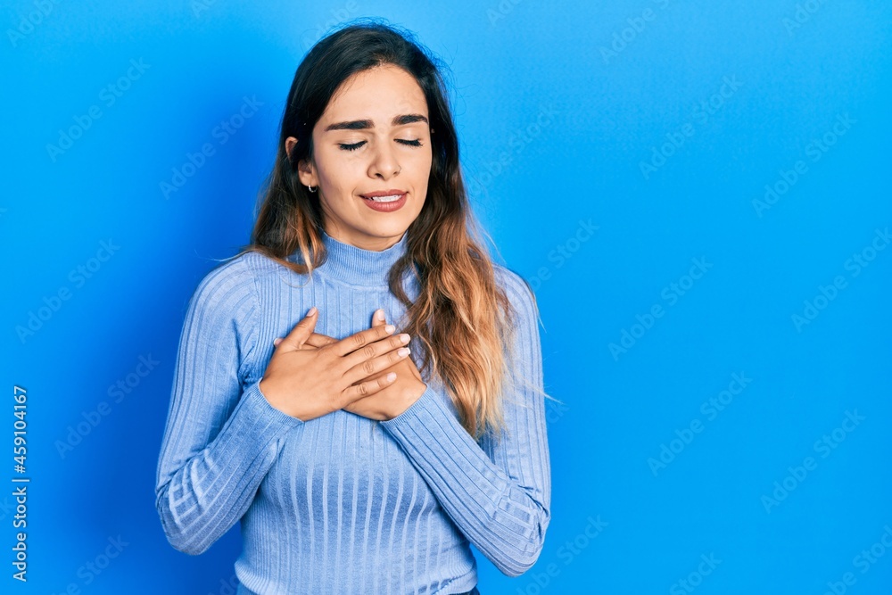 Young hispanic girl wearing casual clothes smiling with hands on chest with closed eyes and grateful gesture on face. health concept. Young hispanic girl wearing casual clothes smiling with hands on chest with closed eyes and grateful gesture on face. health concept.