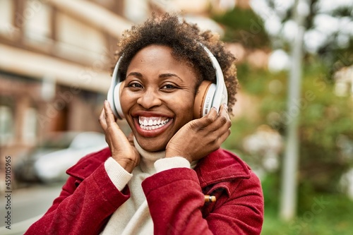 Beautiful african american woman with afro hair smiling happy and confident wearing headphones listening to music
