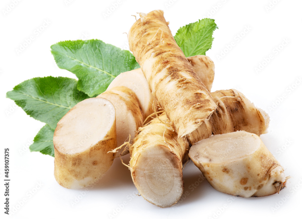 Horseradish roots and green leaves close up on the white background