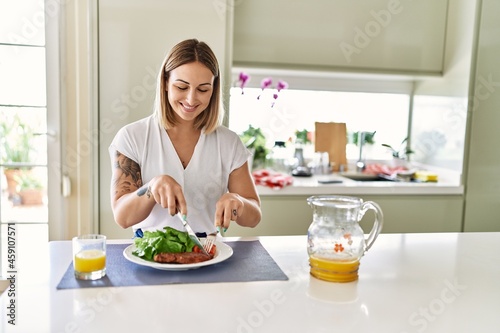 Young caucasian girl smiling happy having lunch at the kitchen.