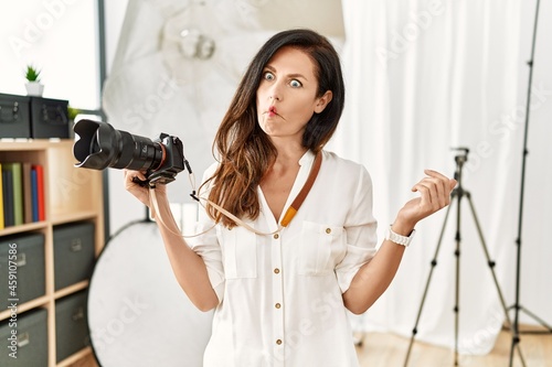 Beautiful caucasian woman working as photographer at photography studio making fish face with lips, crazy and comical gesture. funny expression.