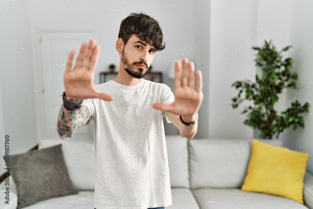 Hispanic man with beard at the living room at home doing frame using hands palms and fingers, camera perspective Hispanic man with beard at the living room at home doing frame using hands palms and fingers, camera perspective