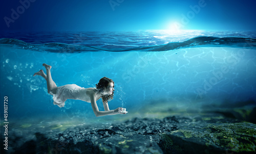 Woman holding a cup underwater