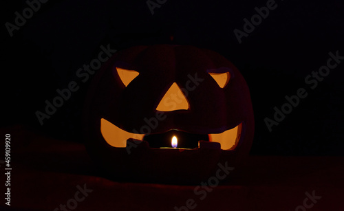 A glowing carved pumpkin in a black background - halloween concept