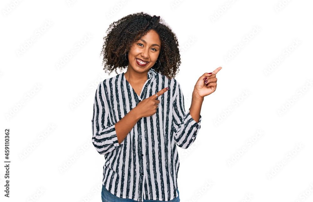 Young african american girl wearing casual clothes smiling and looking at the camera pointing with two hands and fingers to the side. Young african american girl wearing casual clothes smiling and looking at the camera pointing with two hands and fingers to the side.