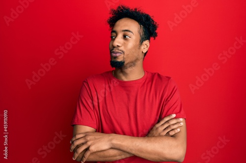 Young african american man with beard wearing casual red t shirt smiling looking to the side and staring away thinking.