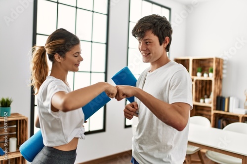 Young caucasian couple after sport smiling happy bump fists at home.