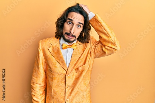 Young hispanic man wearing hipster elegant look confuse and wonder about question. uncertain with doubt, thinking with hand on head. pensive concept.