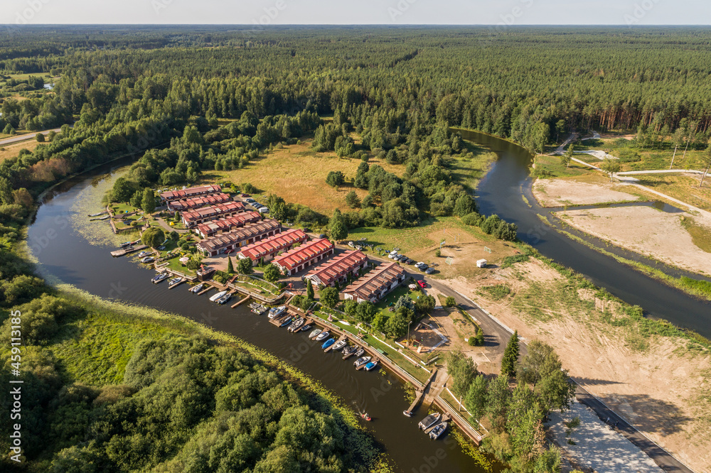 Cottages with red roofs in the forest by the river. Aerial view.