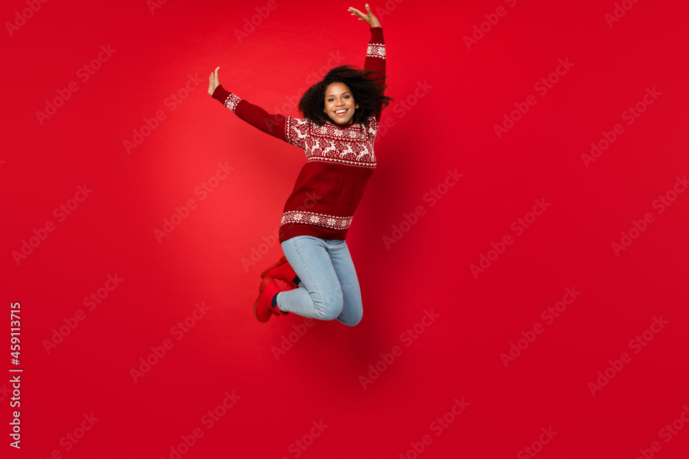 Full length body size photo woman jumping up in ornamented sweater isolated bright red color background