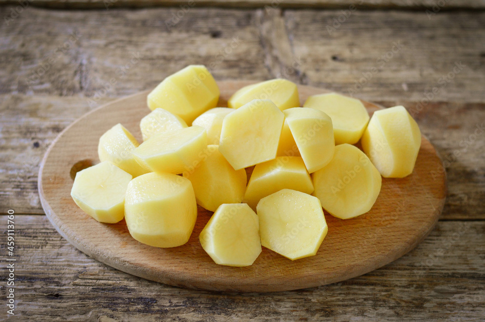 Peeled and sliced ​​potatoes on wooden background
