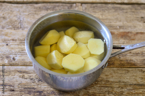 Boiled potatoes in a saucepan on a wooden background