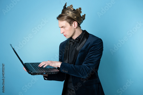 businessman with a crown on his head uses a laptop and a phone.