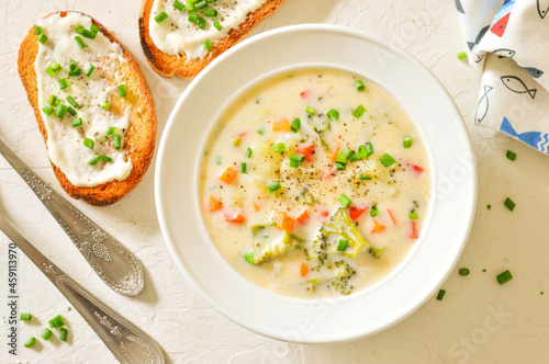 Cheese (creamy) soup with broccoli, carrots, herbs, croutons. White dishes and white background. Horizontal
