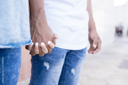 Close up of romantic couple holding hands while standing on street. Midsection of couple romancing on vacation. Close up of couple holding hands in denim jeans