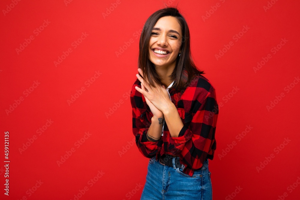 Photo of young beautiful happy smiling brunette woman wearing trendy white t-shirt and red check shirt . Sexy carefree female person posing isolated near red wall in studio with free space. Positive Photo of young beautiful happy smiling brunette woman wearing trendy white t-shirt and red check shirt . Sexy carefree female person posing isolated near red wall in studio with free space. Positive