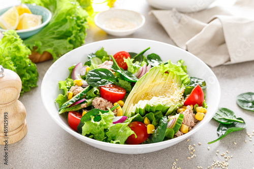 Avocado and tuna fresh vegetable salad with tomato, cucumber corn, onion, lettuce and spinach. Healthy and detox food concept. Ketogenic diet. Buddha bowl dish on light background.