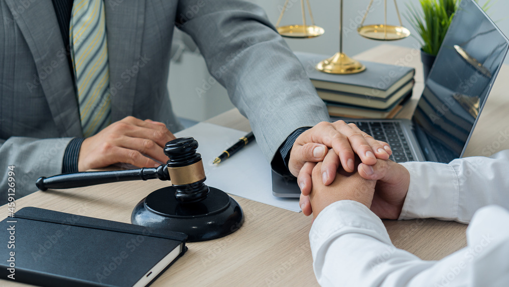 Attorney-consultants hold clients' hands with trust. The center of lawyers and clients are discussing on a table with scales and hammers with laptops and notebooks. legal advisor concept