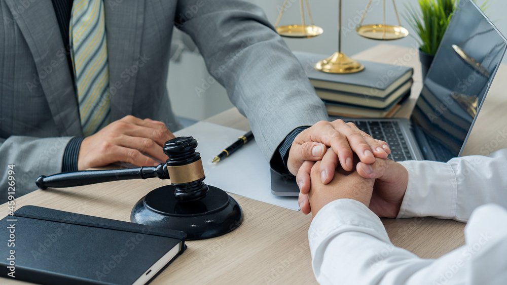Attorney-consultants hold clients' hands with trust. The center of lawyers and clients are discussing on a table with scales and hammers with laptops and notebooks. legal advisor concept Attorney-consultants hold clients' hands with trust. The center of lawyers and clients are discussing on a table with scales and hammers with laptops and notebooks. legal advisor concept
