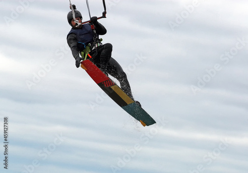 Trick by kitesurfer man in high jump