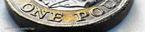 The British 1 pound sterling coin close-up. Banner or headline about economy, money or banking in England. Focus is on the nominal value. UK currency. Macro