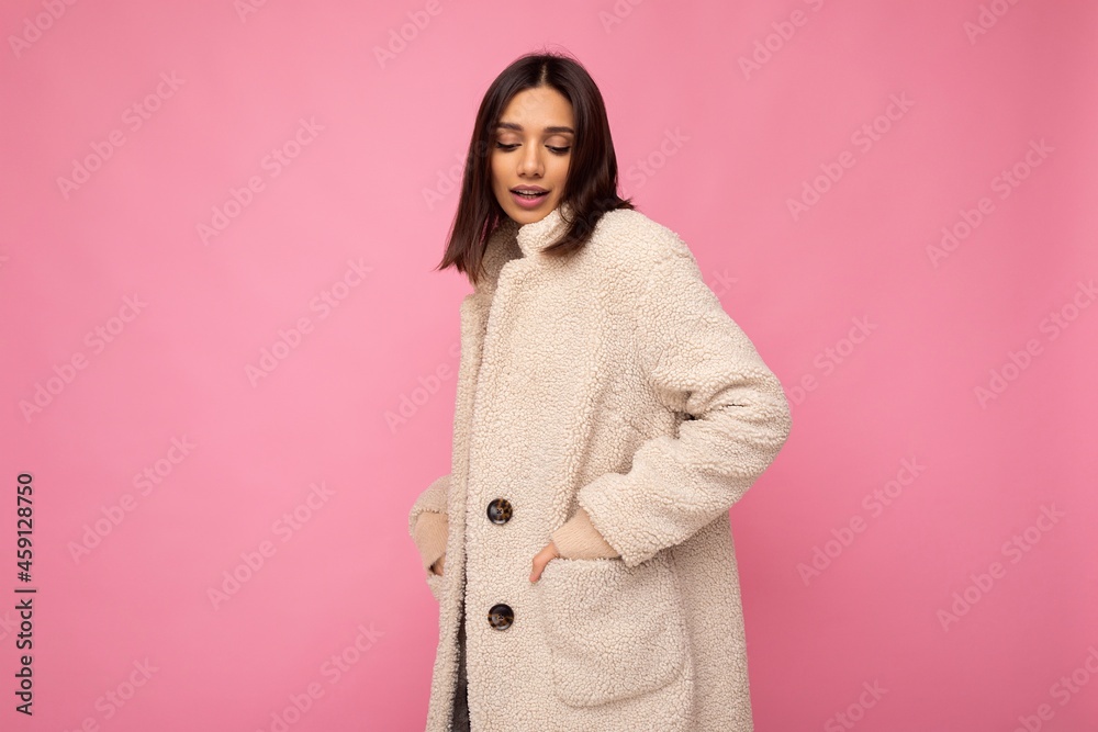 Caucasian photo of attractive self-confident stylish young brunette woman wearing autumn beaige warm coat isolated on pink background with empty space. Fashion concept