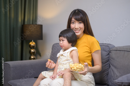 Happy mom and daughter watching movie and relaxing at home