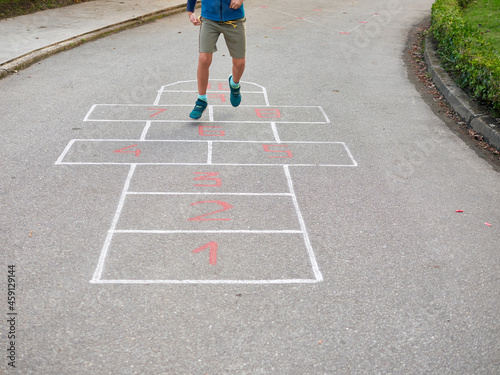 Young boy jumping and playing hopscotch  no faces shown