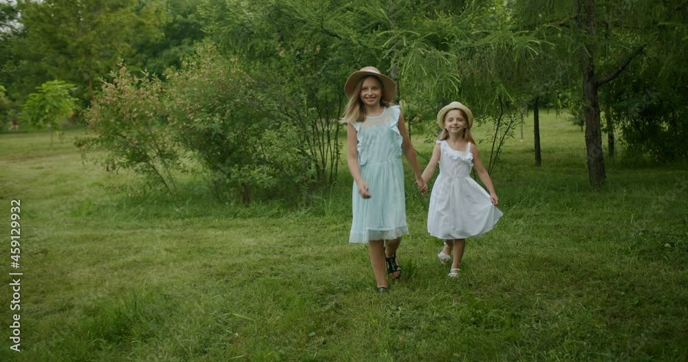 two little girls walk hand in hand in the beautiful green ecological park, two little girls walk hand in hand in the beautiful green ecological park,