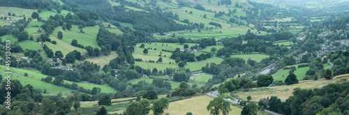 Panorama landscape image of Peak District National Park valley in English countryside during late Summer hazy evening
